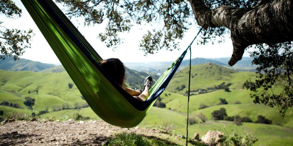 kobieta w hamaku na tle gór; jak wykorzystać wakacje w zmianie zawodowej